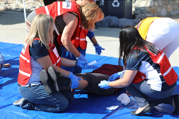 Multiple building marshals in red vests helping an injured person